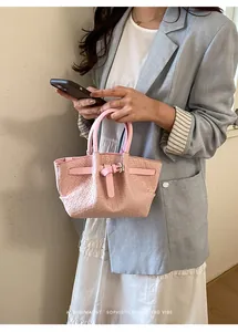Chic pink bucket bag with woven texture styled with a white dress and blue blazer