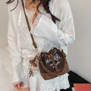 Large brown canvas bucket bag with cat print and bear charm on female model