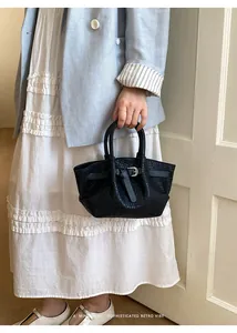 Close-up of black woven leather handbag showing detailed texture and silver buckle strap