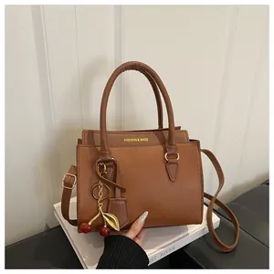 Sac à main marron en cuir texturé avec pendentif cerise et bandoulière amovible