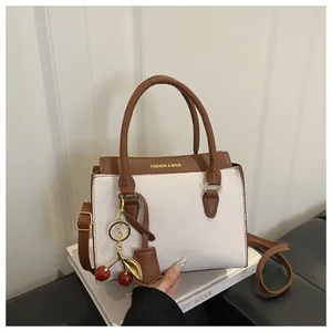 Détail du sac en cuir texturé litchi avec breloque cerise et lettrage mode