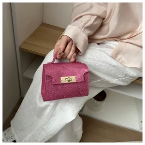 Detail of fuchsia mini square handbag with pebbled texture and gold twist lock clasp
