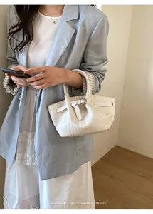 Detail showing white woven texture and silver metal buckle on minimalist bucket bag