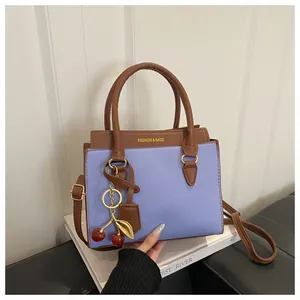 Détail du sac à main lilas et marron avec un pendentif cerise scintillant élégant