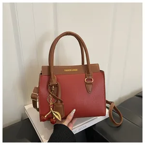 Vue détaillée du sac en cuir rouge avec texte doré et pendentif cerise élégant