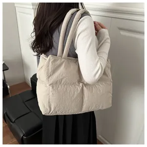 Beige quilted puffer tote bag on shoulder showing soft texture and large capacity