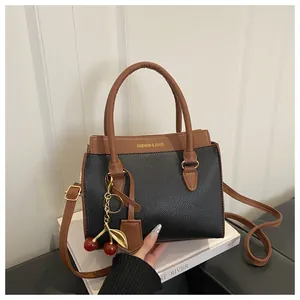 Détail du sac à main en cuir grainé avec pendentif cerise et logo texte mode