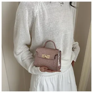 Detail of rose gold mini handbag with snake pattern texture and gold twist lock