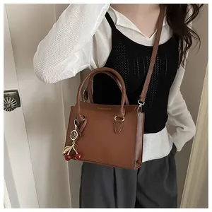 Sac à main marron en cuir avec double poignée et porte-clés cerise en métal chic