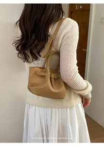 Detail of khaki woven bucket bag with adjustable silver buckle strap and minimalist design