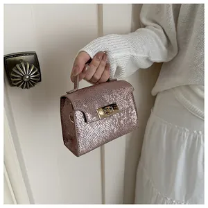 Close-up of pink snakeskin texture handbag with gold rotating metal lock detail