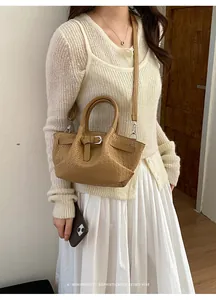 Close-up of khaki woven texture handbag with metal buckle and detachable strap