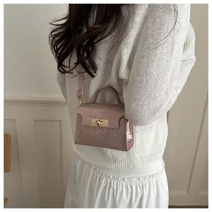Detail of metallic pink crossbody bag with cracked texture and gold lock hardware