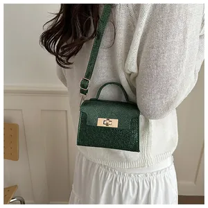 Detail of dark green textured leather mini bag featuring golden twist lock and top handle