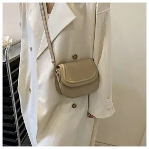 Close-up of beige vintage saddle bag worn with a classic trench coat style