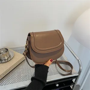 Retro brown leather saddle bag with gold buckle and adjustable strap shown by model