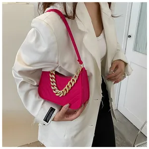 Detail of pink felt baguette bag with gold chain strap on a white blazer outfit