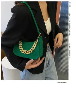 Fashionable vintage green felt underarm bag with gold chain strap on model's shoulder