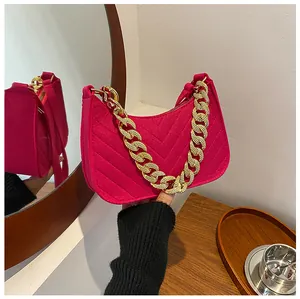 Detail of fuchsia felt baguette bag with V-shaped stitching and chunky gold chain strap