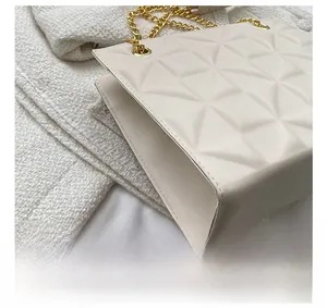 Detail view of the geometric quilted texture and gold chain on this cream crossbody bag