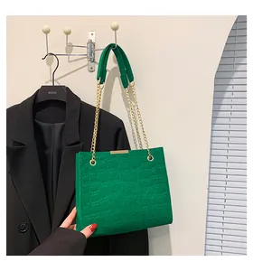 Detail einer hellgrünen Tasche mit Krokoprägung und einer markanten goldfarbenen Kette