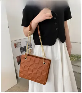 Detail of brown quilted crossbody bag with golden chain strap and 3D textured leather