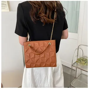 Back view of model wearing a caramel brown quilted leather crossbody bag with gold chain