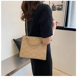 Detail of beige geometric textured crossbody bag with gold chain strap on shoulder