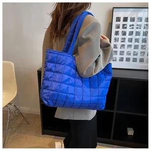 Detail of blue quilted tote bag with padded nylon texture and long shoulder straps