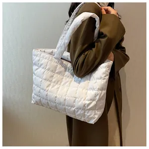 Detailed view of white quilted puffer tote bag with large square stitching and wide strap