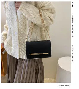 Détail d'un petit sac bandoulière en cuir noir avec barre dorée et chaîne élégante