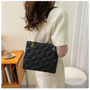 Detail of black quilted leather crossbody bag featuring a chunky gold chain strap