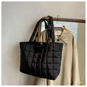 Close-up of black quilted nylon tote bag with magnetic closure on wooden hanger
