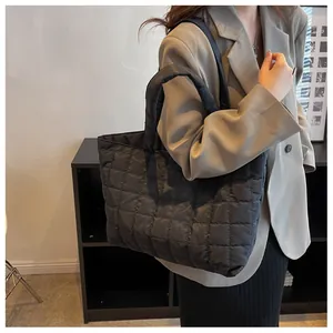 Detail of black quilted puffer tote bag with thick padded handles for stylish winter commute