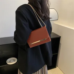 Sac bandoulière marron rouge chic avec chaîne dorée et finitions métalliques élégantes
