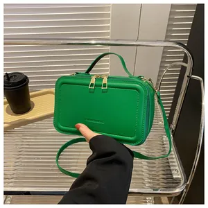 Close-up of green PU leather crossbody bag featuring fashion text and gold metal zippers