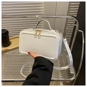Detail of white rectangle handbag with embossed lettering and gold zipper closure