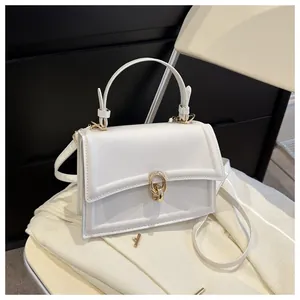 Detail of white faux leather crossbody bag with top handle and gold metal lock