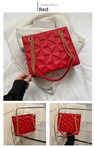 Detail view of red shoulder bag with 3D geometric texture and golden chain strap
