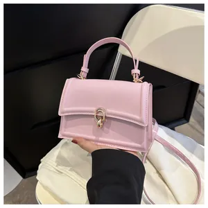 Close-up of pink crossbody bag with a round gold buckle detail and sleek leather finish
