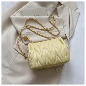 Close-up of cream quilted crossbody bag with gold chain and adjustment ball detail