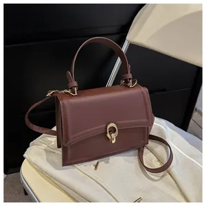 Detail view of smooth chocolate brown PU leather bag with elegant gold metal twist lock