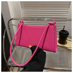 Détail du sac baguette fuchsia avec lettrage doré et bandoulière à nœud décoratif
