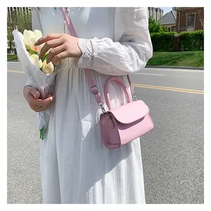 Detailed view of pink minimalist leather crossbody bag with envelope flap and top handle