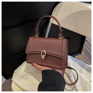 Detailed macro view of the vintage brown leather bag with a golden oval metal fastener