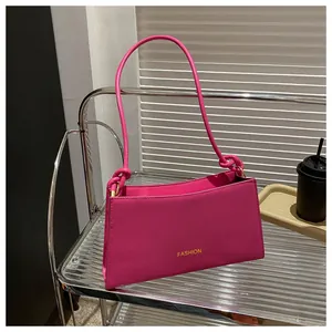 Détail du sac baguette rose fuchsia avec bandoulière nouée et finitions dorées