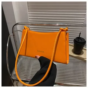 Détail du sac baguette orange vif avec texte FASHION et bandoulière à nœuds