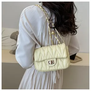 Detail of light yellow quilted crossbody bag with gold chain and spherical metal bead