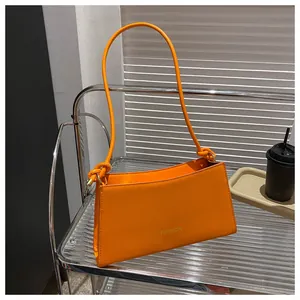 Détail du sac baguette orange vif avec logo fashion et bandoulière à nœuds
