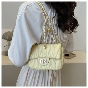 Detail of wave quilted flap bag with golden ball adjustable chain strap worn by model